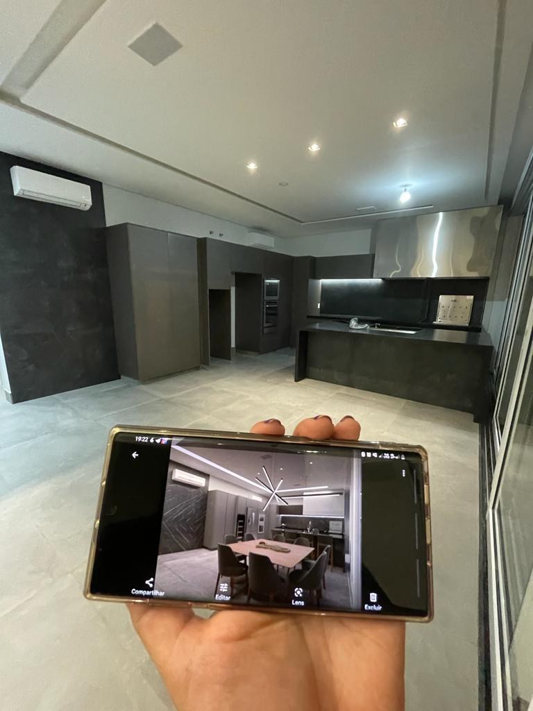 Hand holding a phone with the 3D render in front of the finished kitchen and living space on site