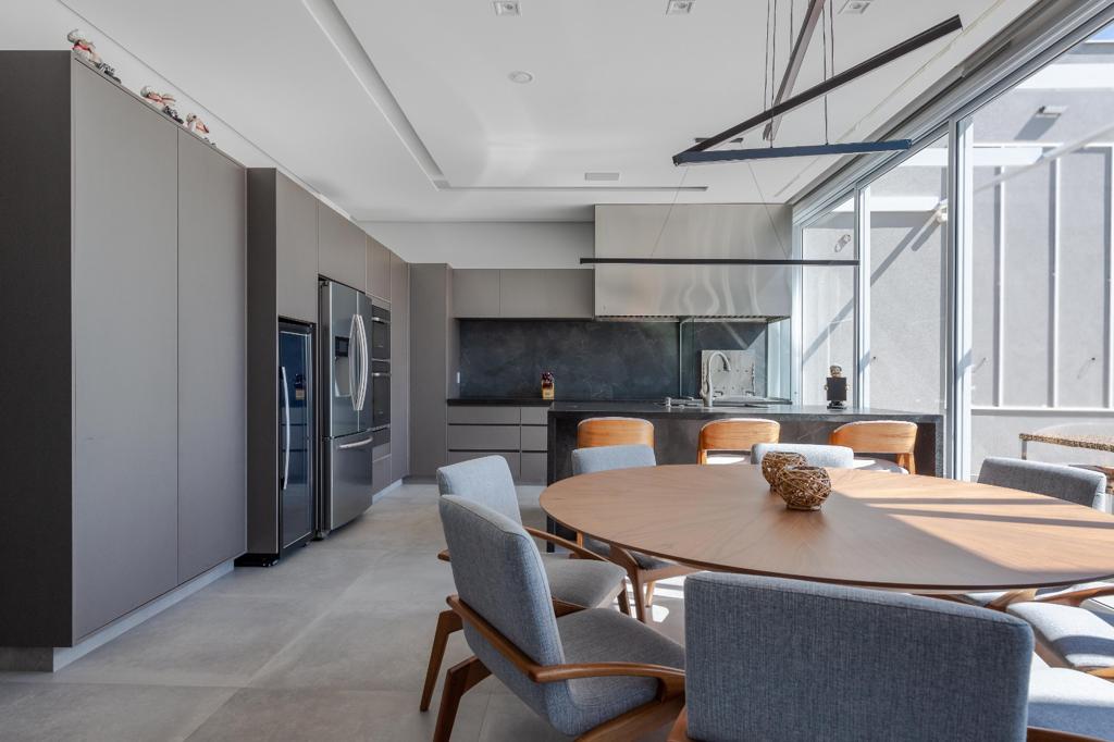 The same kitchen and dining area today, finished, with gray millwork, stone backsplash and a round wood dining table